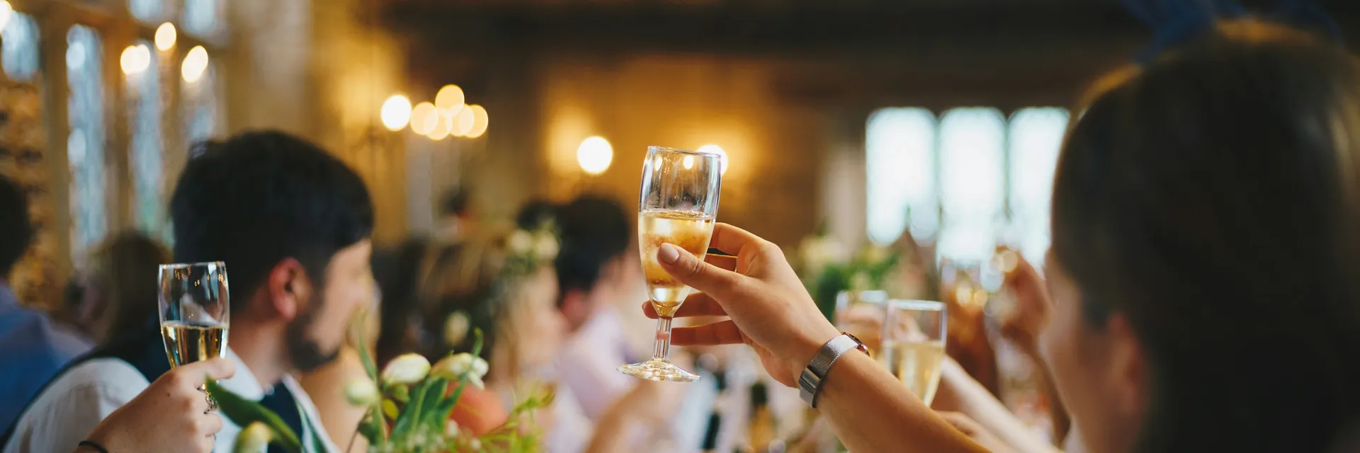 Guests raising a toast together under warm string lights