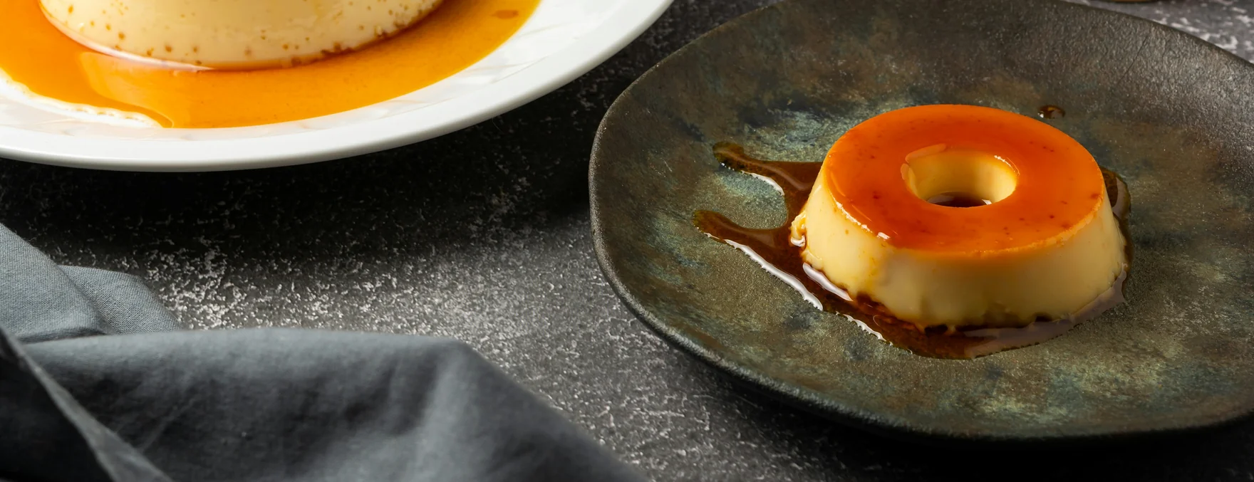 Flan with cajeta caramel on a dark ceramic plate