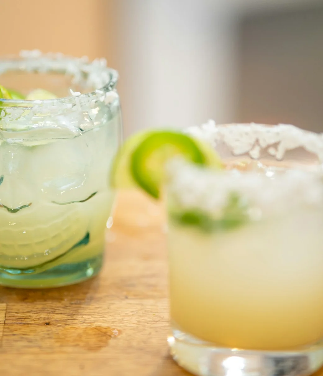 Two house margaritas with salted rims and fresh lime