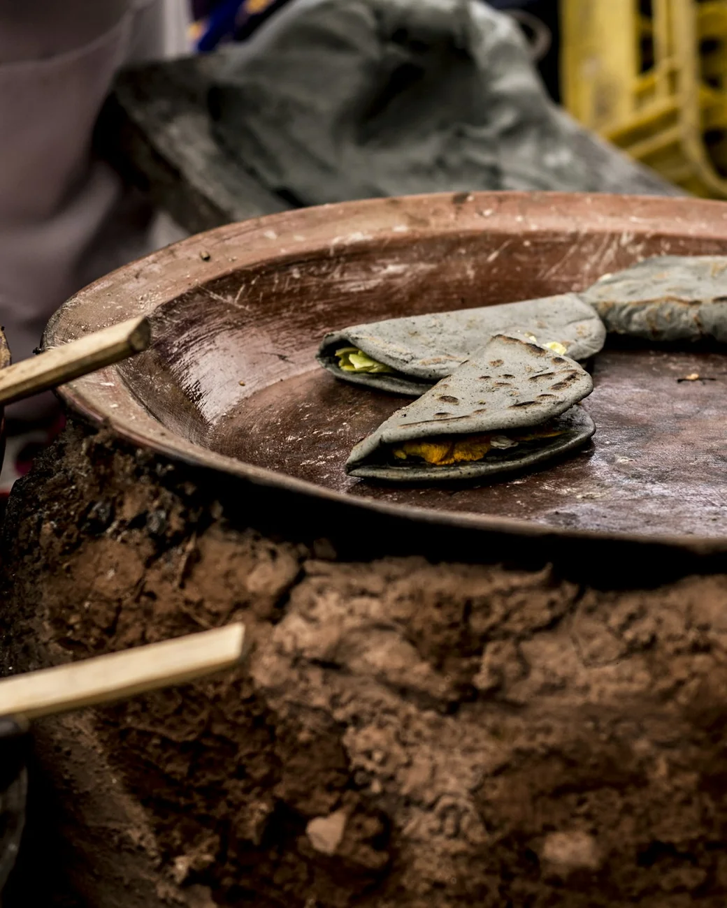 Tortillas cooking on a clay comal over an open wood fire