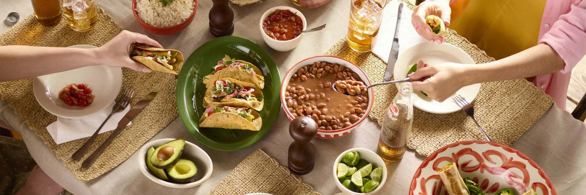An overhead view of a table set with tacos, charro beans, guacamole and limes