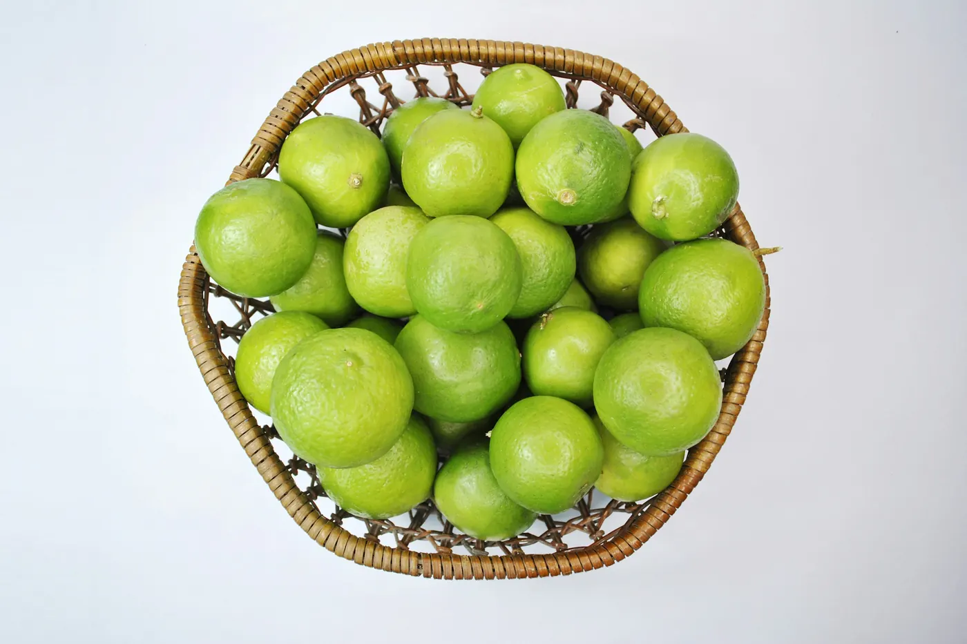 A woven basket of bright green tomatillos still in their husks