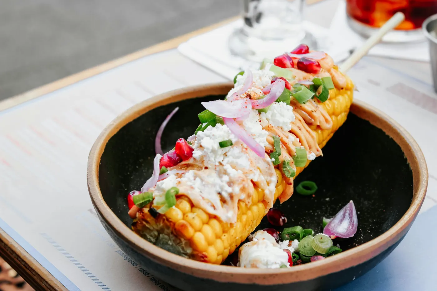 A bowl of corn kernels dressed with crema, cheese and chile