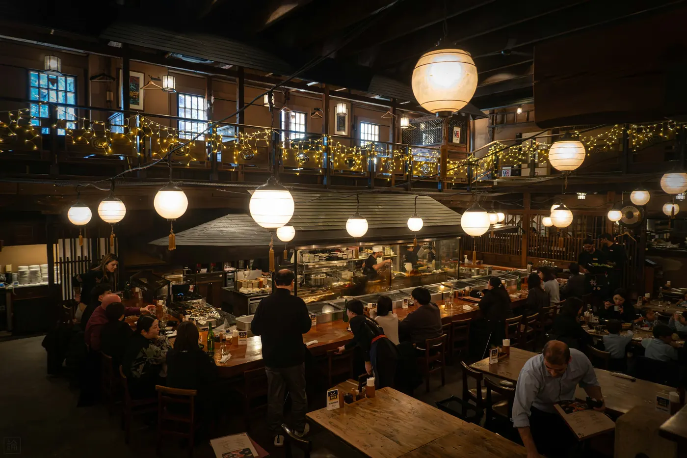A busy restaurant dining room lit by hanging lamps