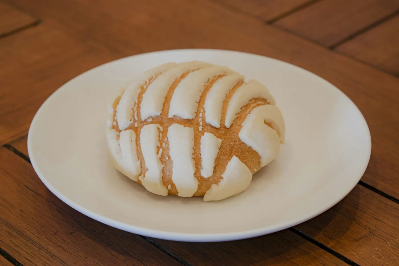 A round sweet bread with a patterned sugar topping on a white plate