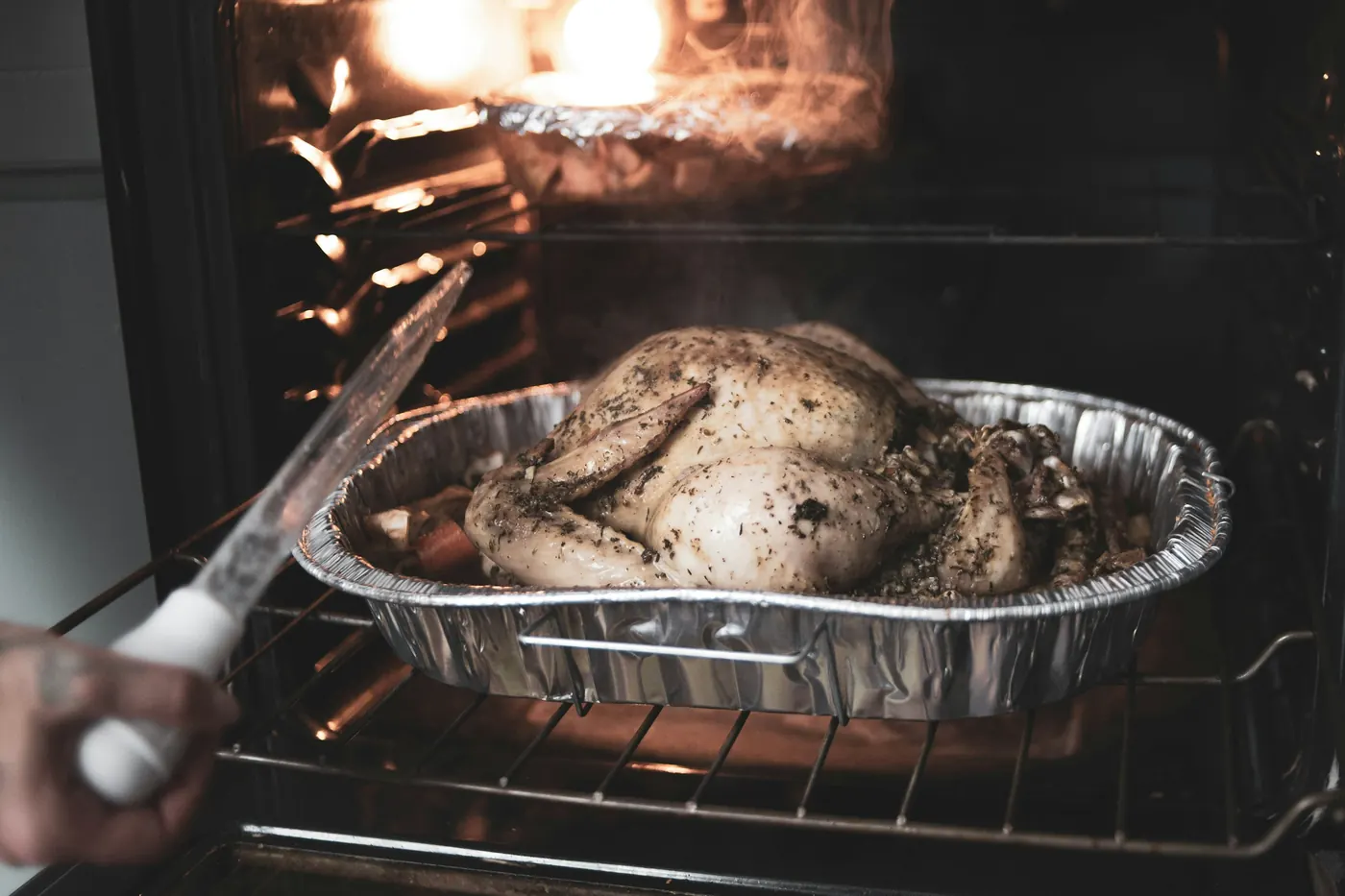 A covered roasting dish being placed into a hot oven