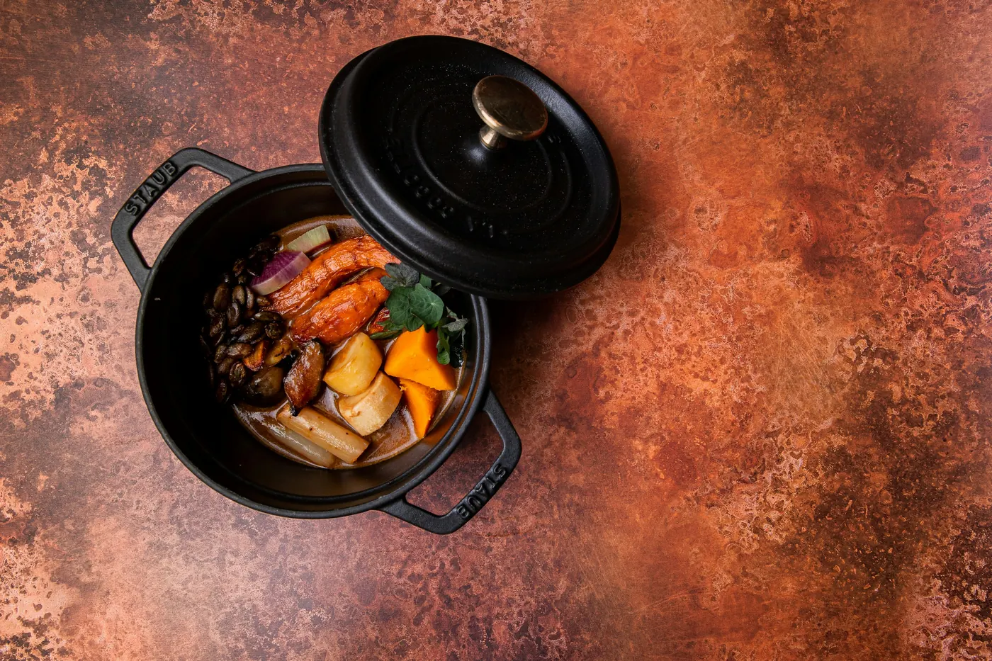 A small lidded pot holding braised meat and vegetables