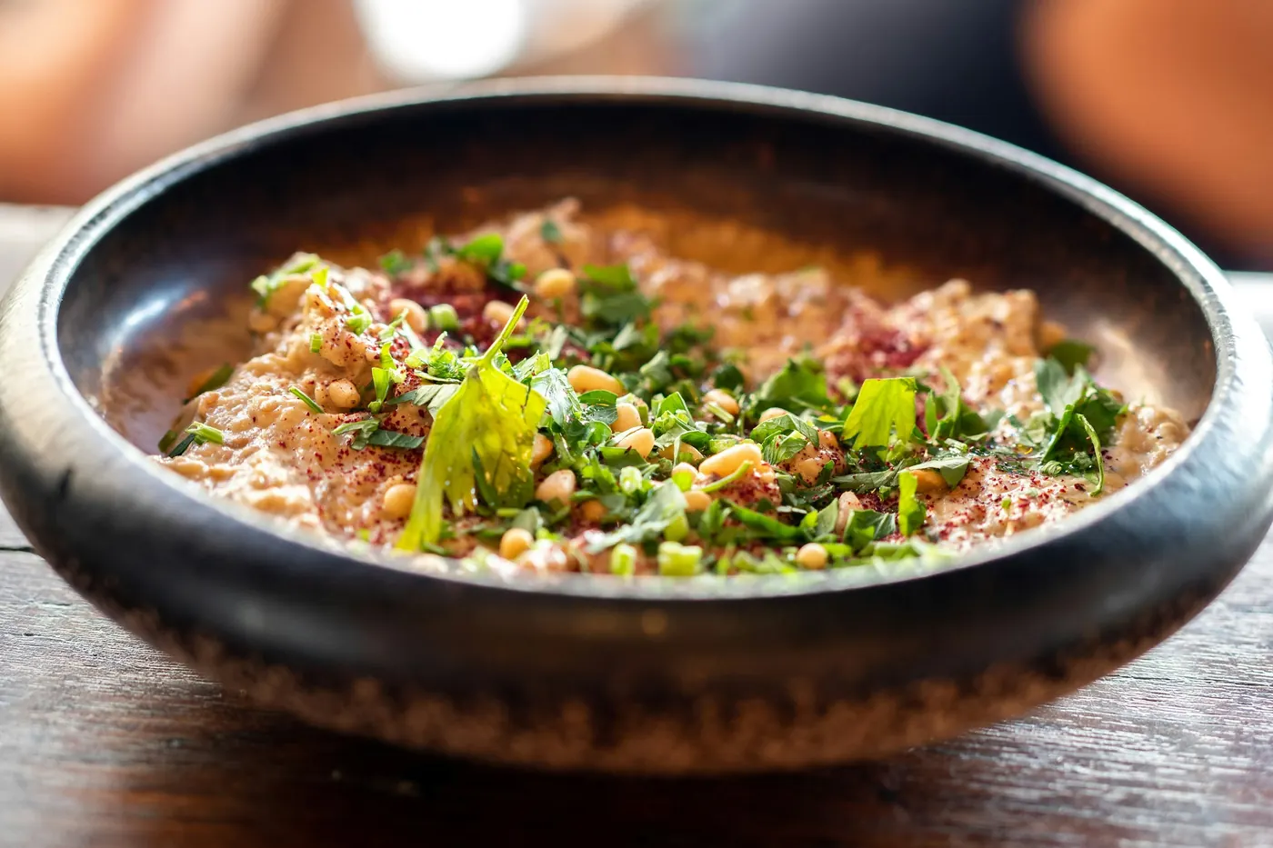 A dark bowl of stewed beans finished with chopped herbs and onion