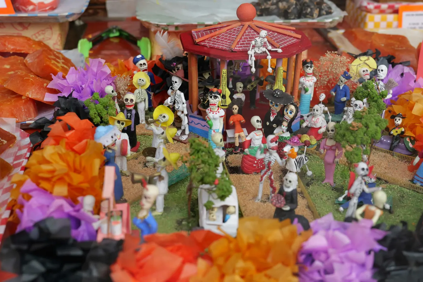 A colorful altar covered with skeleton figures, flowers and offerings