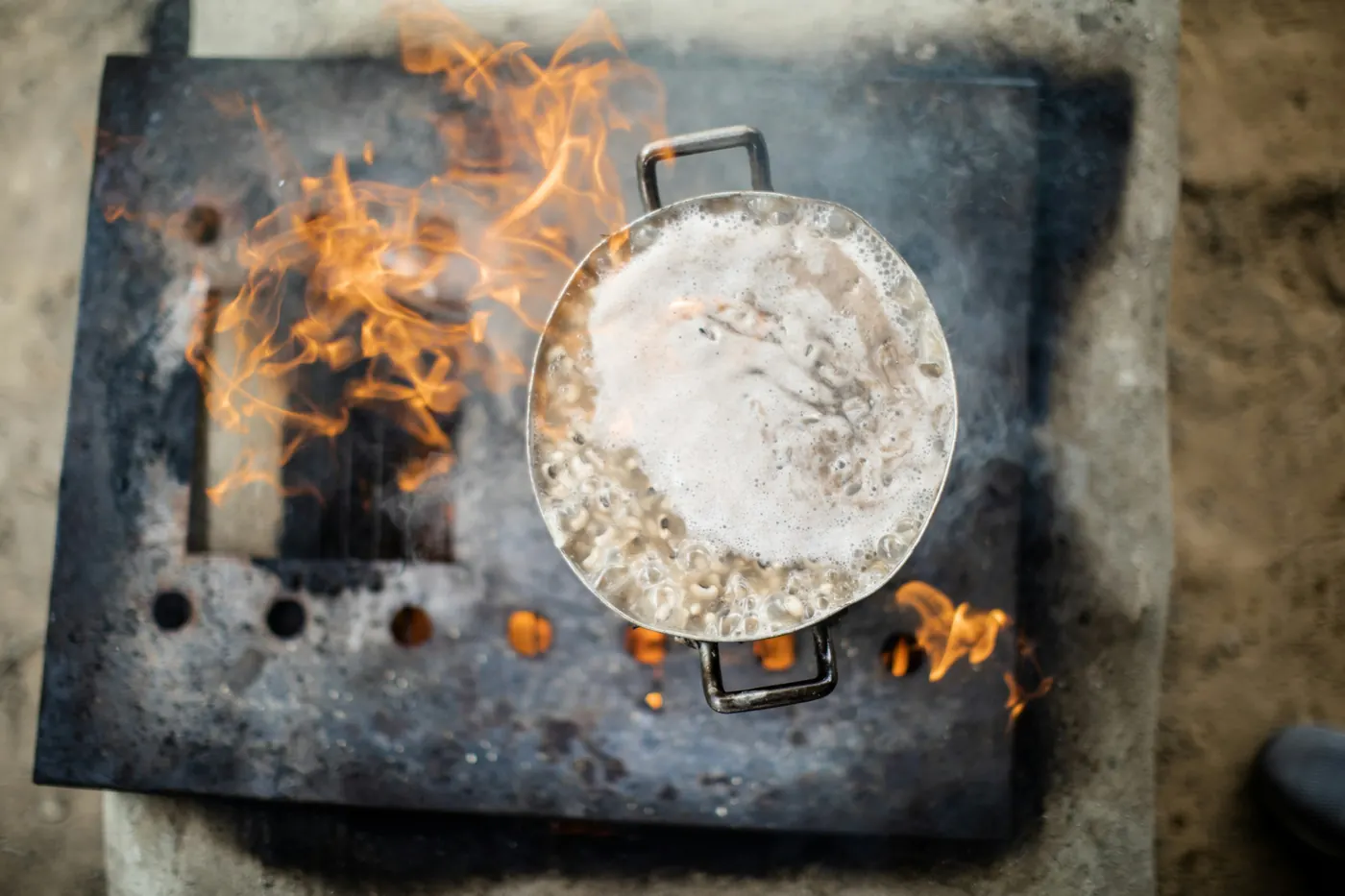 A flat metal cooking plate set over open flame