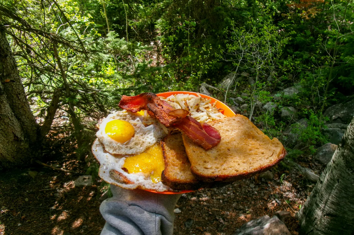 A fried egg served on a flat bread base, held up outdoors
