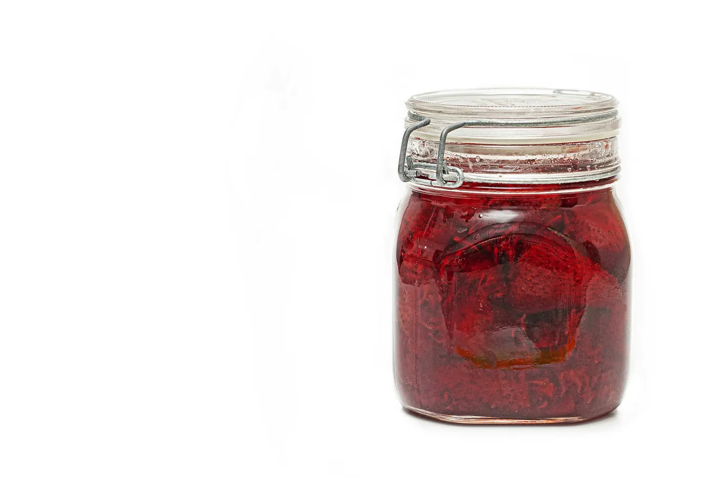 A glass jar packed with deep red pickled onions