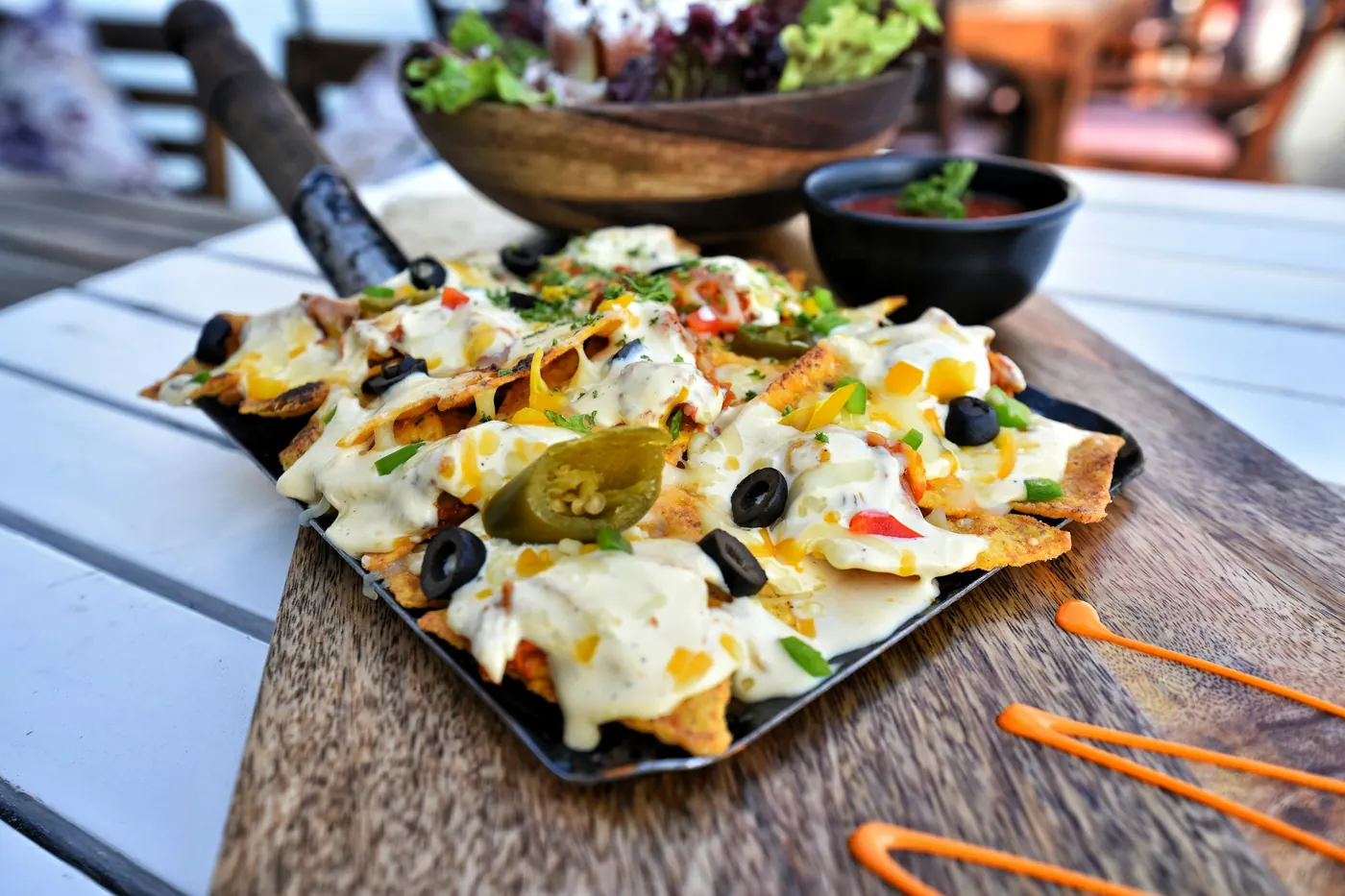 A large platter of nachos loaded with cheese, olives and toppings