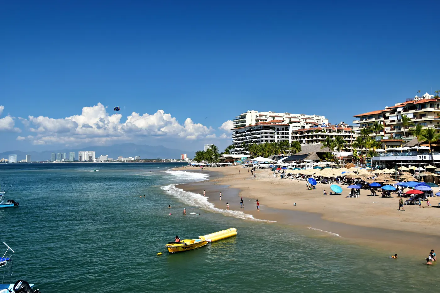 A wide beach and coastal town under a bright blue sky
