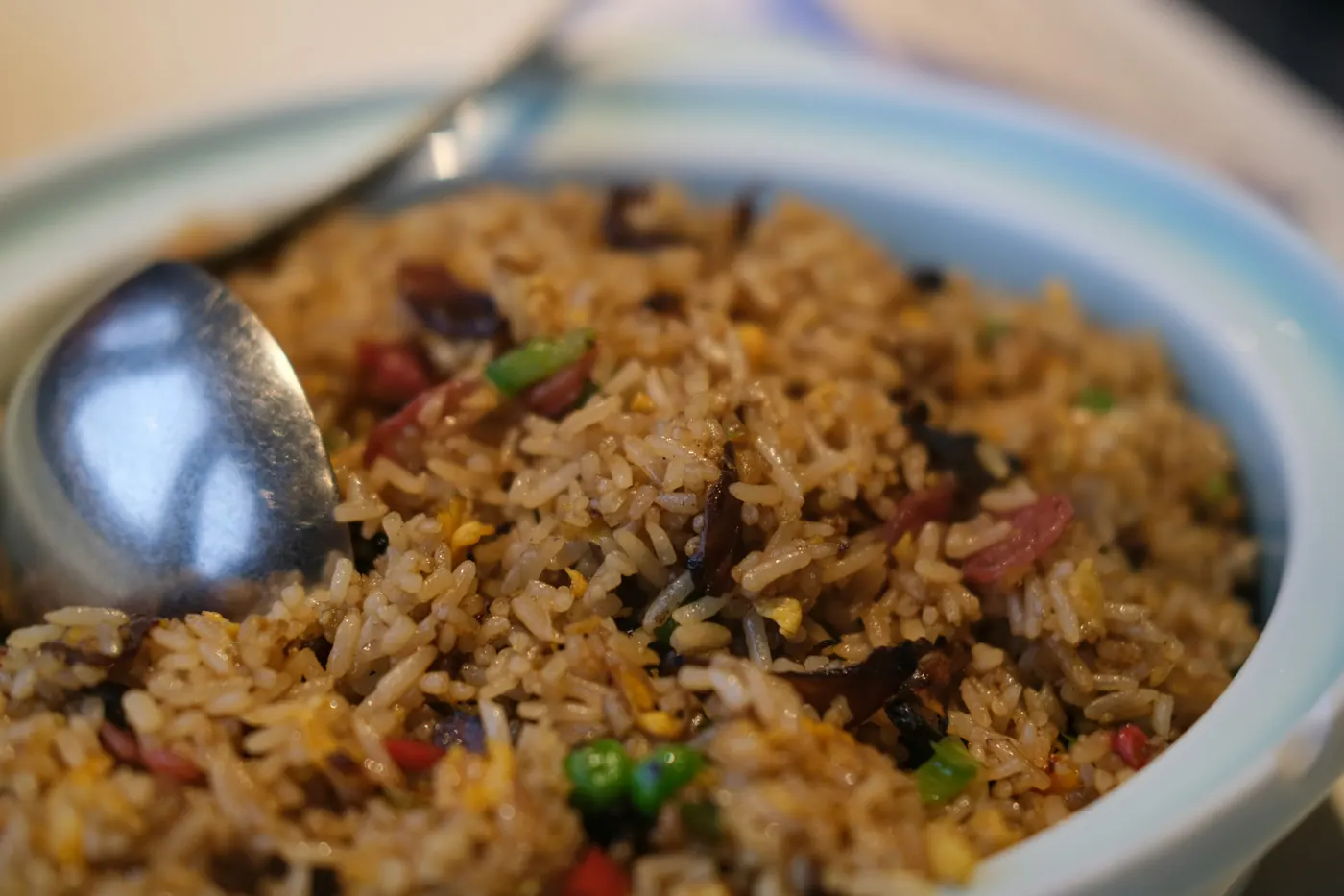 A pan of orange rice studded with vegetables and a serving spoon