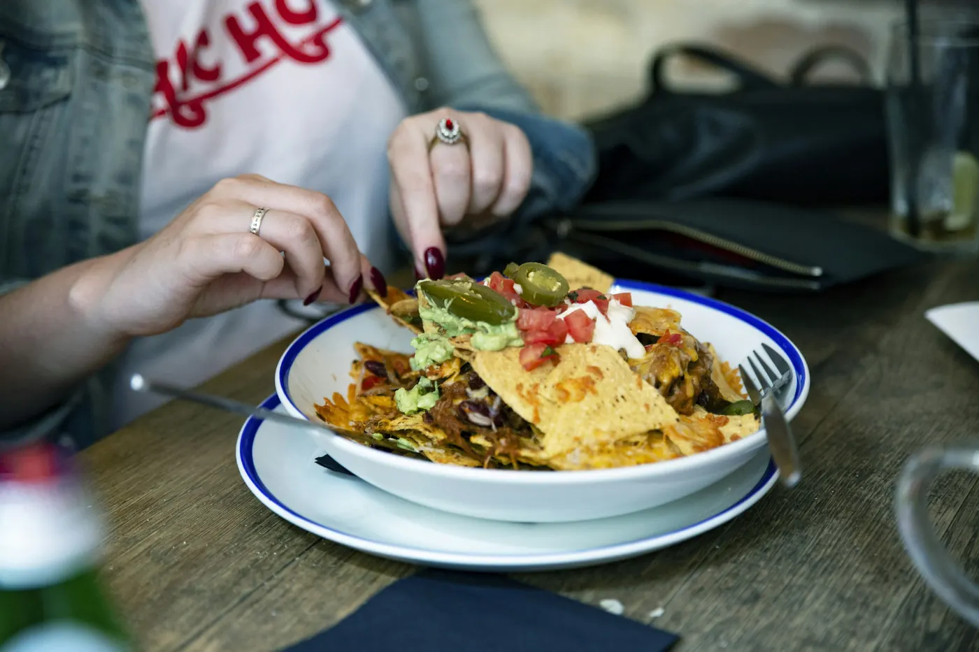 A person reaching into a plate of nachos on a table