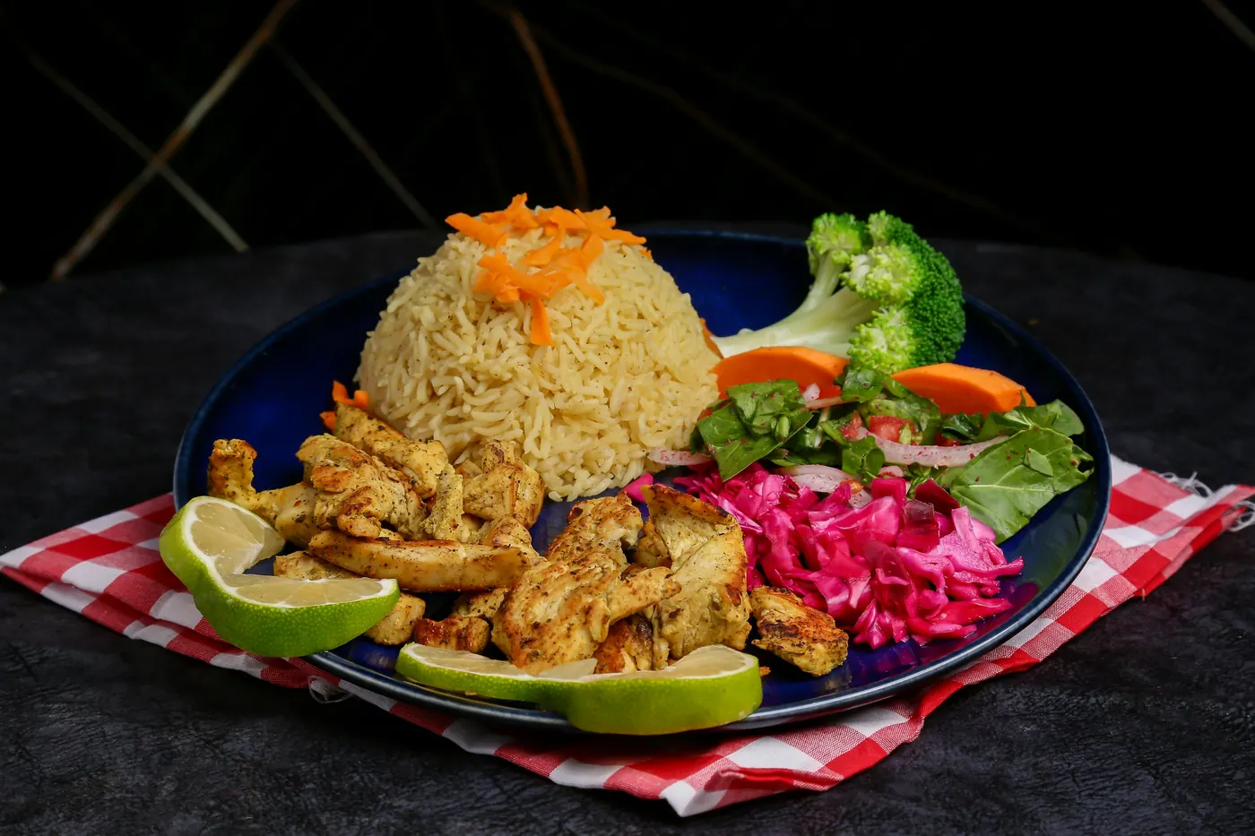A plate of rice and grilled chicken finished with pickled onion and lime