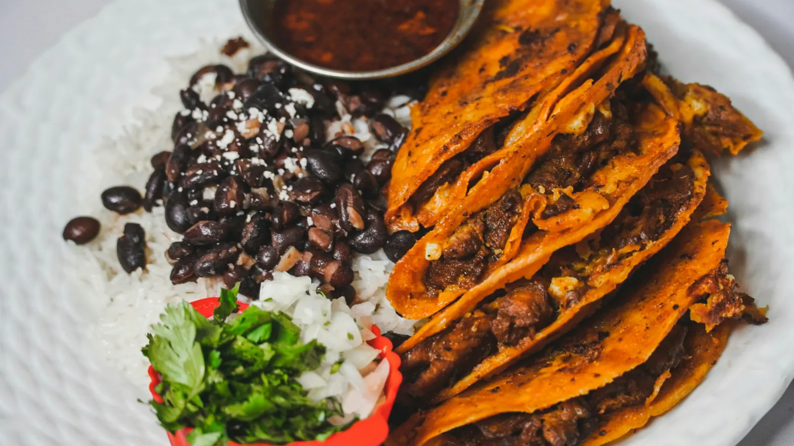 A plate of black beans and rice beside a main dish with cilantro