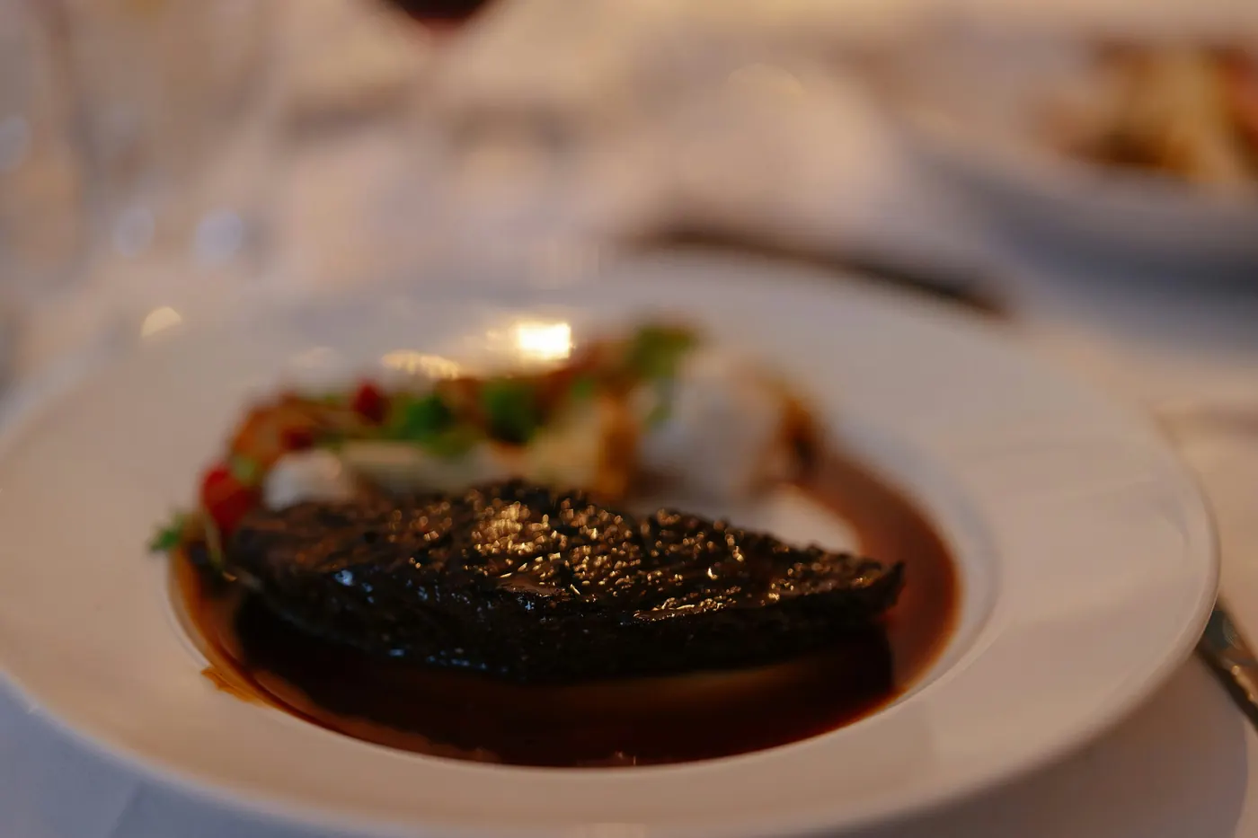 A plated dish sitting in a pool of dark glossy sauce