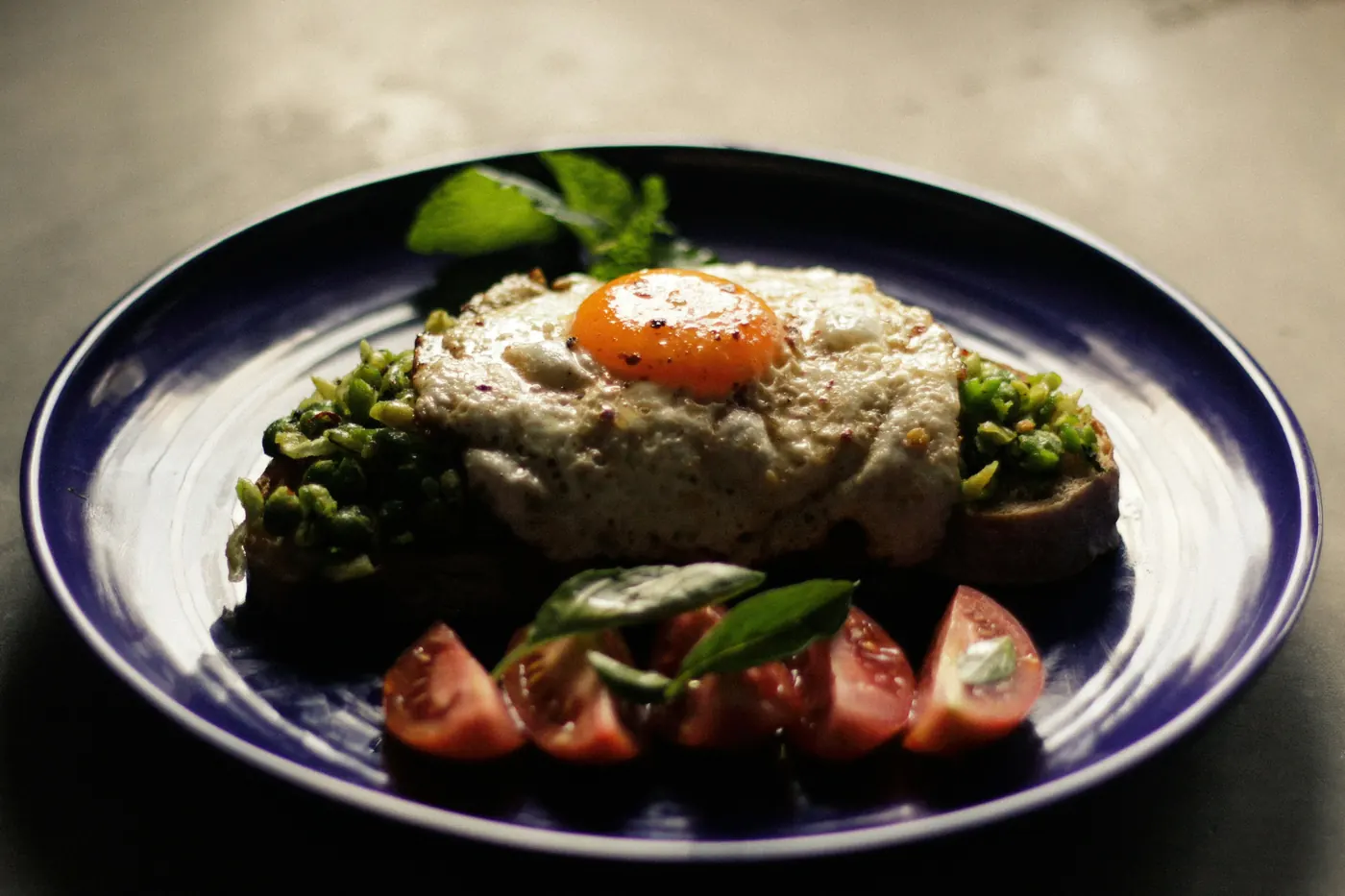 A single egg dish plated carefully on dark crockery