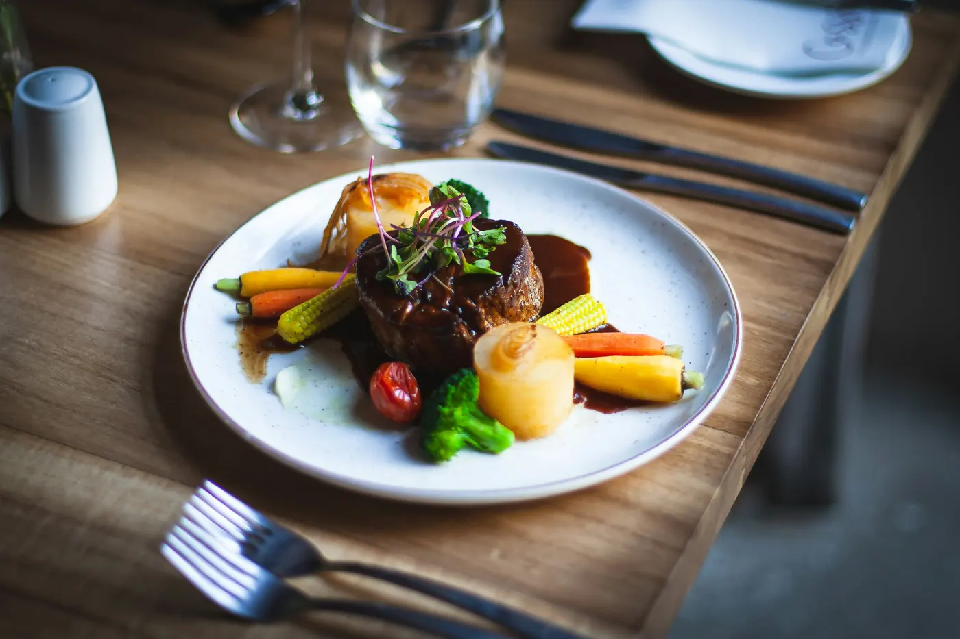A plated main course with meat and vegetables on a wooden table