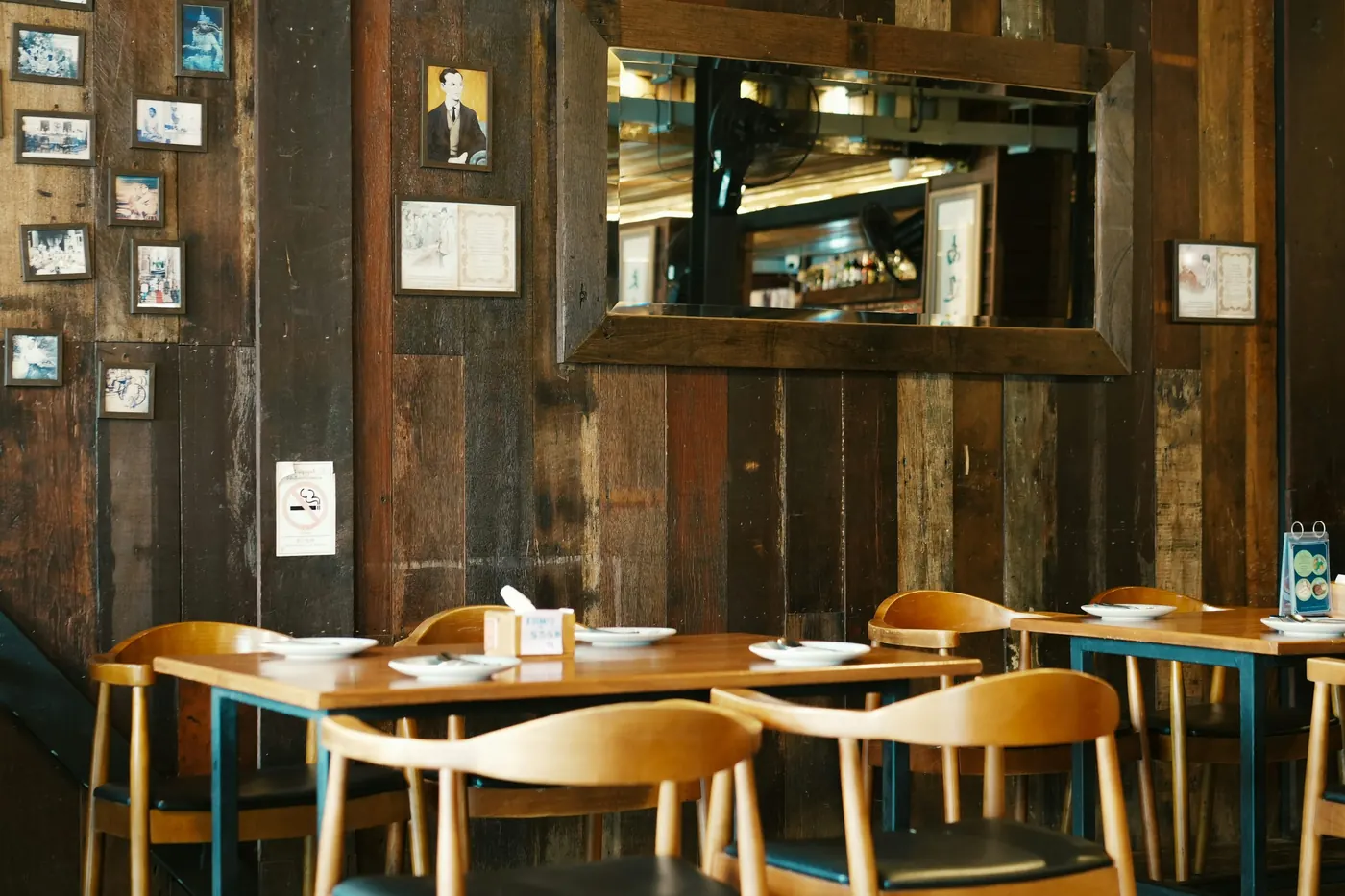 A dining room with wooden tables and chairs set for service