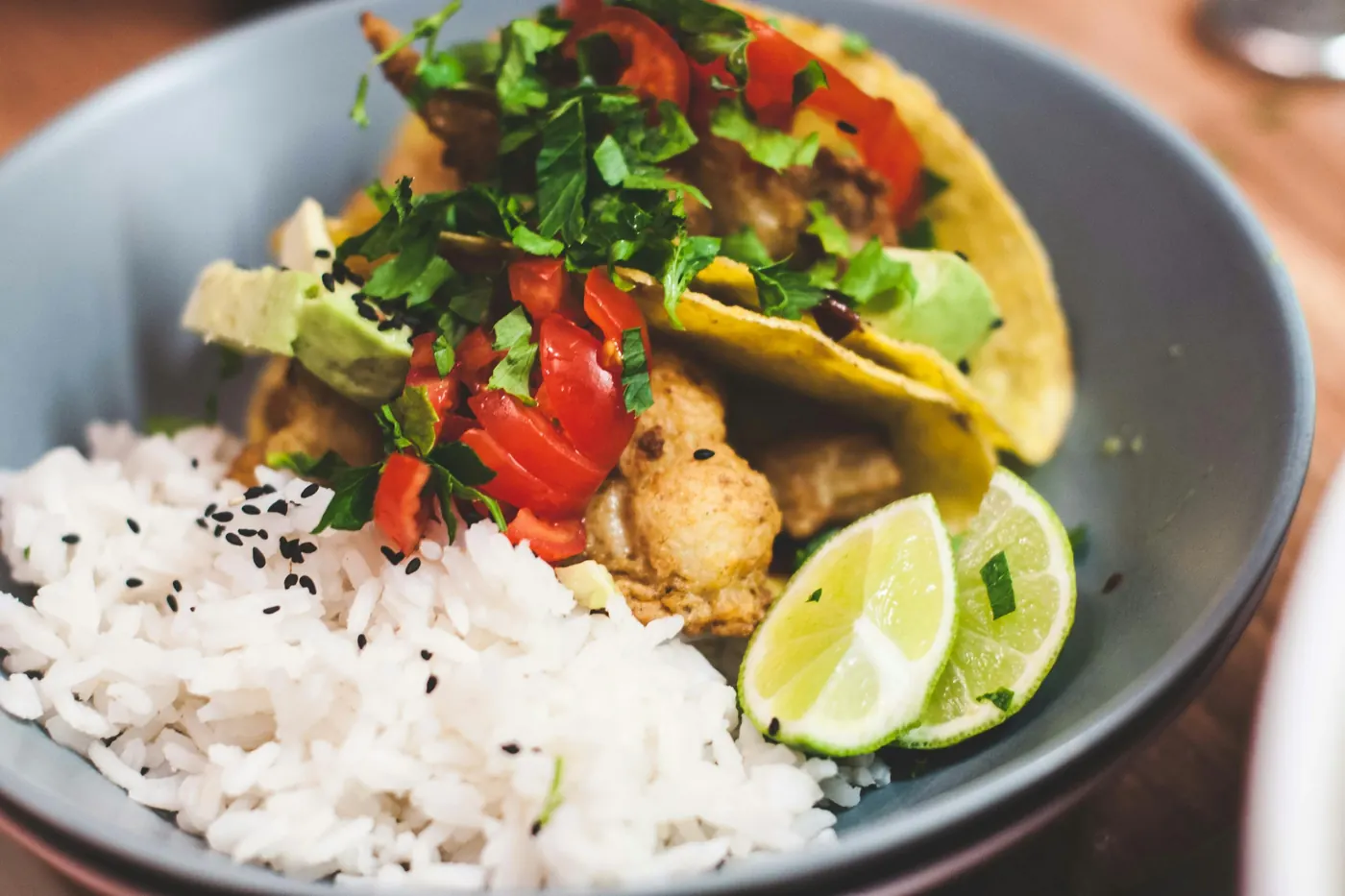 A bowl of shrimp with white rice, avocado and lime