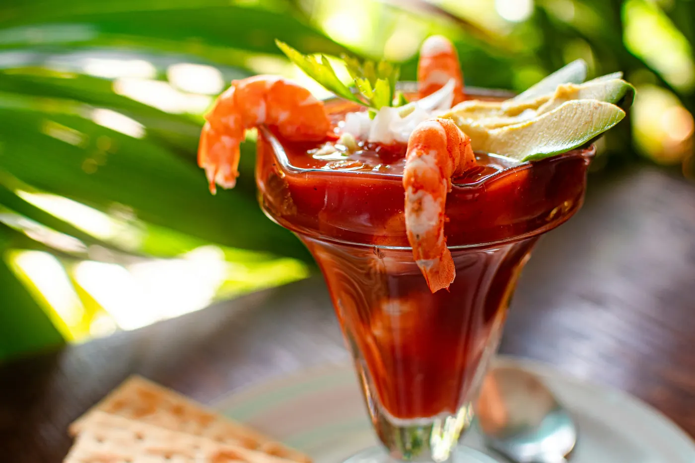 Shrimp hooked over the rim of a glass filled with a red tomato base