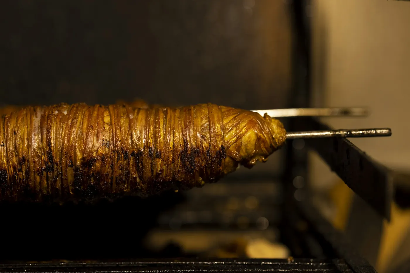 A vertical spit of meat turning against a dark background
