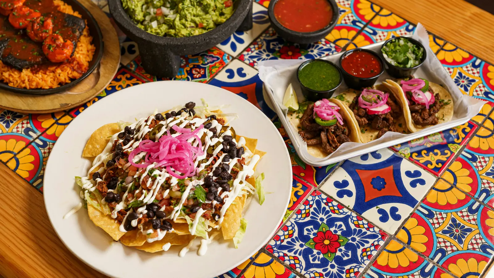 Several Mexican dishes spread across a brightly tiled table