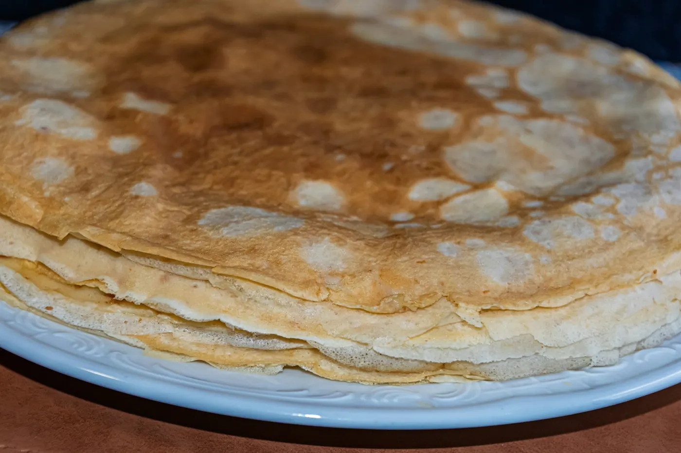 A stack of thin pale corn tortillas on a plate