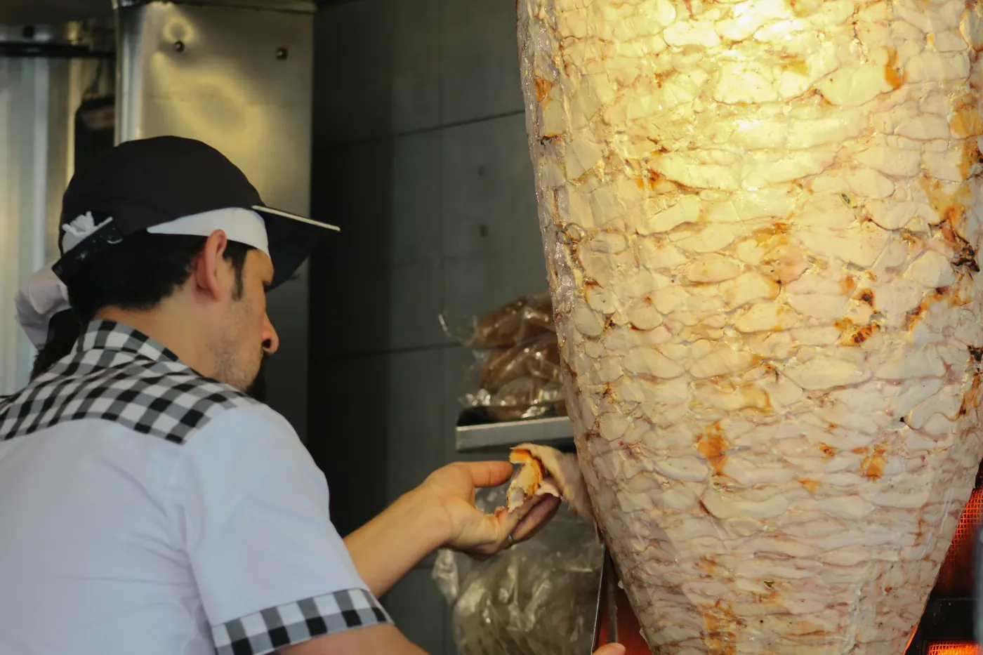 A tall stack of marinated meat on a vertical rotisserie