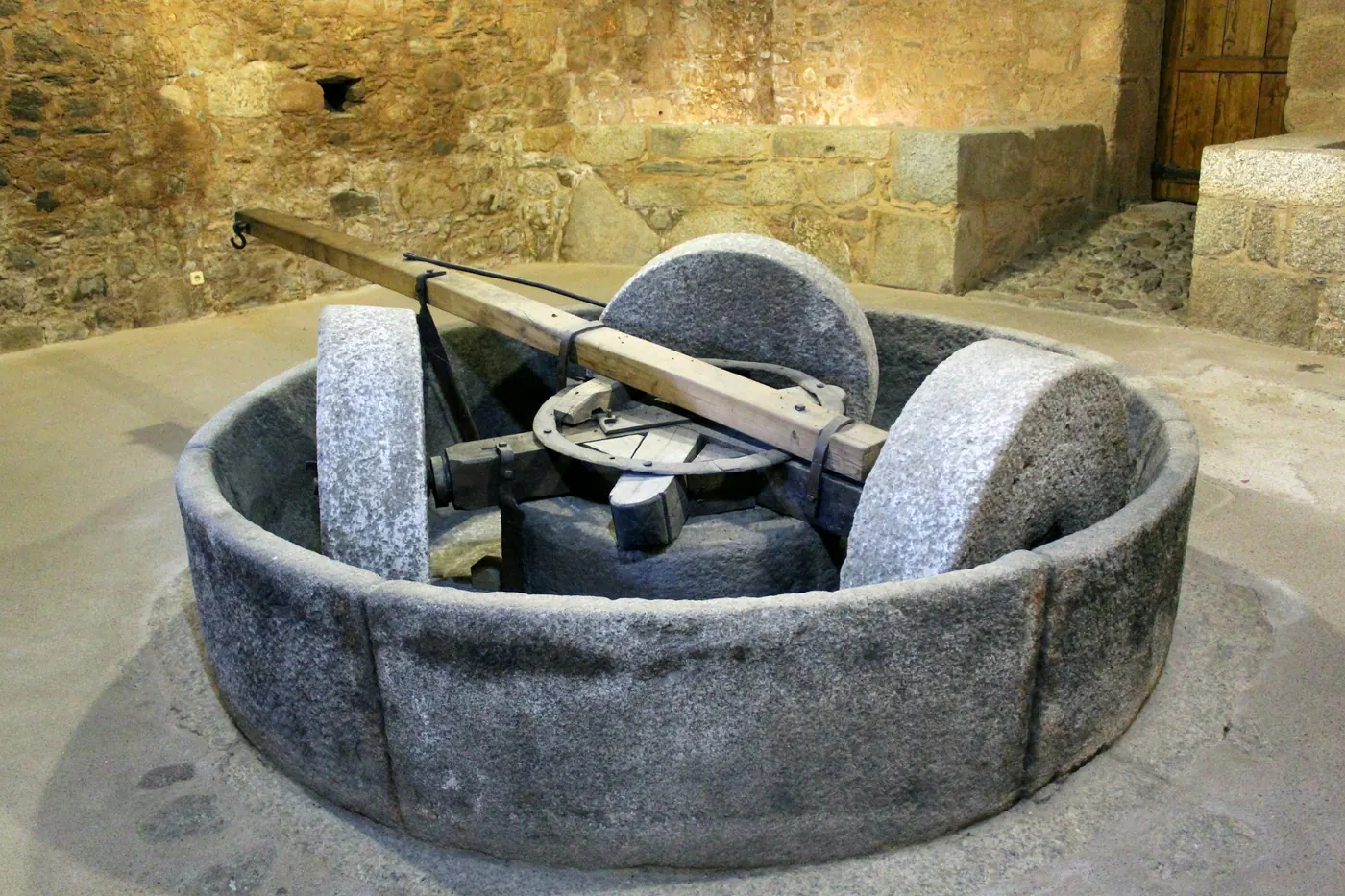 A large circular stone mill set into a shallow stone pit