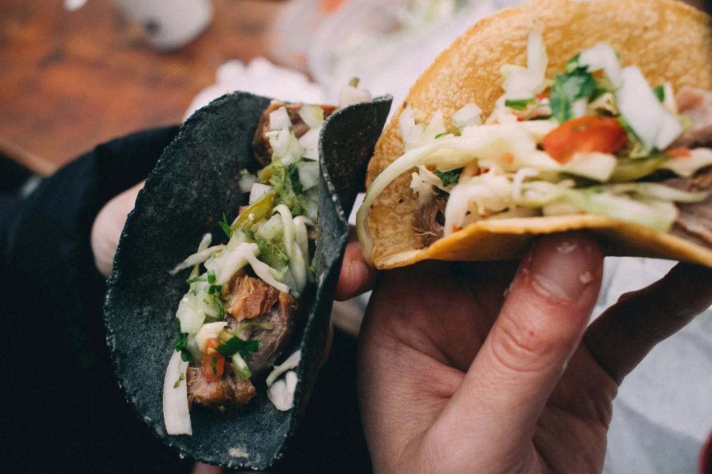 A hand holding a filled taco, the tortilla visible underneath