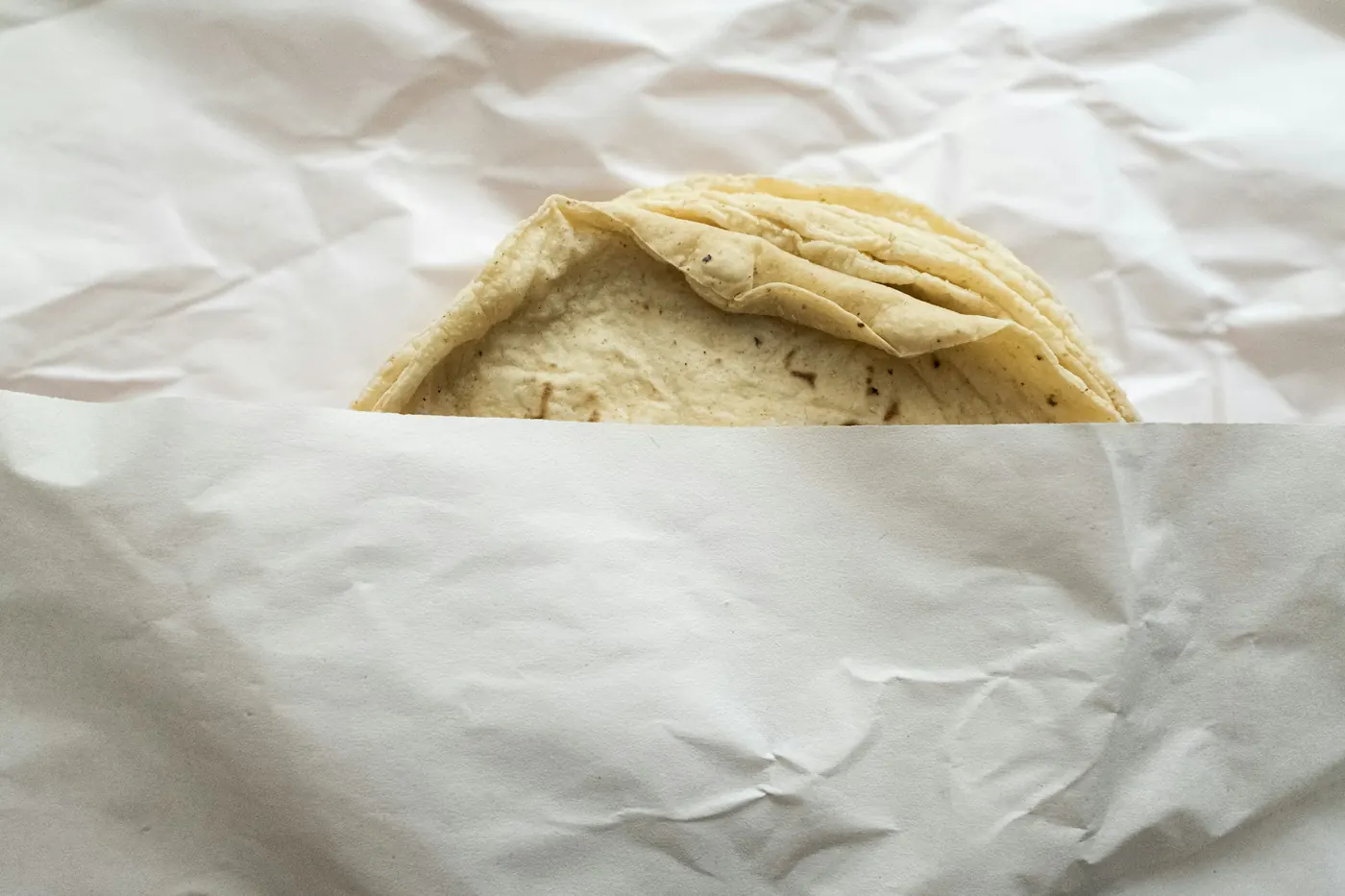 A single soft tortilla wrapped in white paper