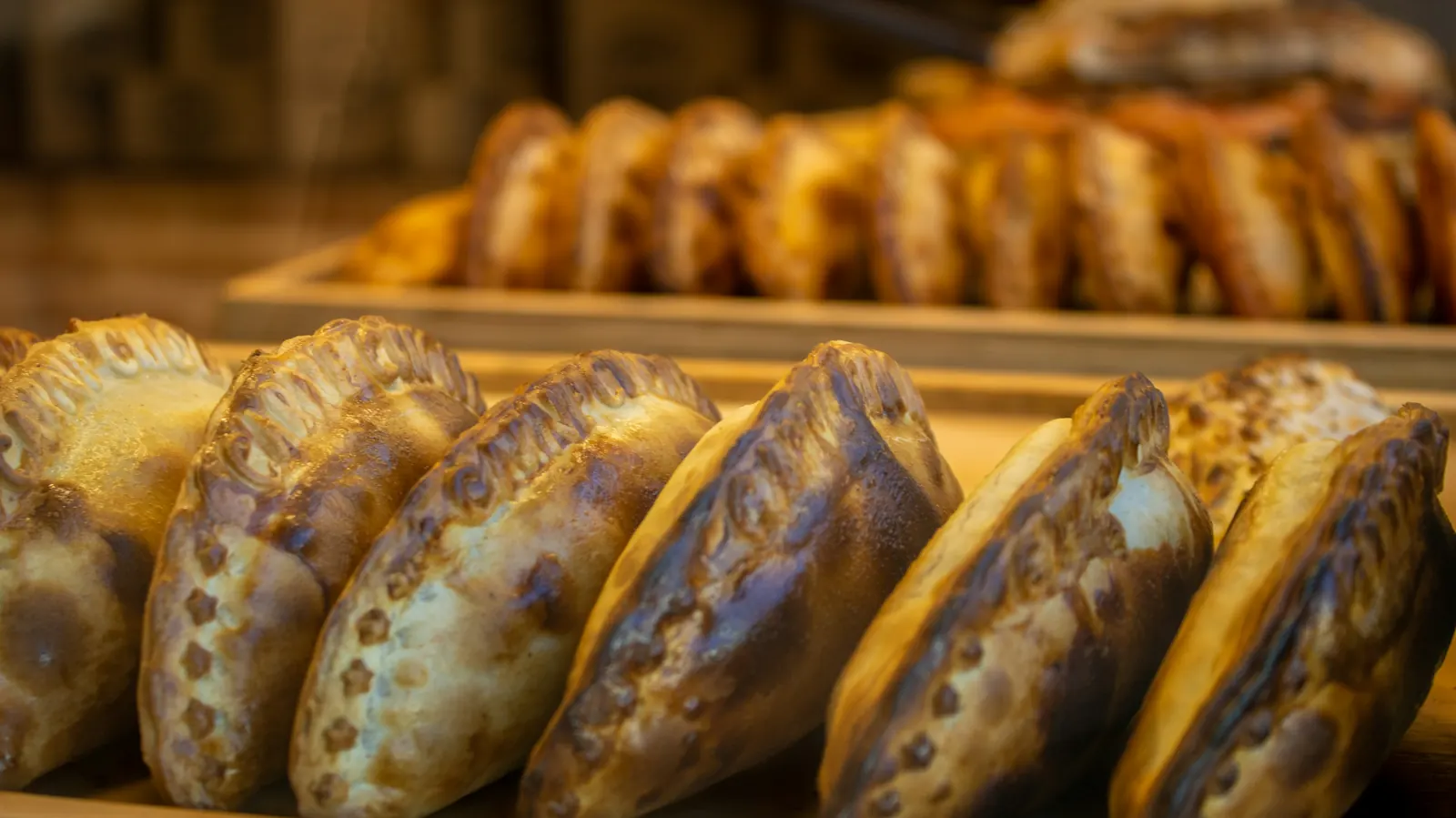 A tray of golden baked empanadas with crimped edges