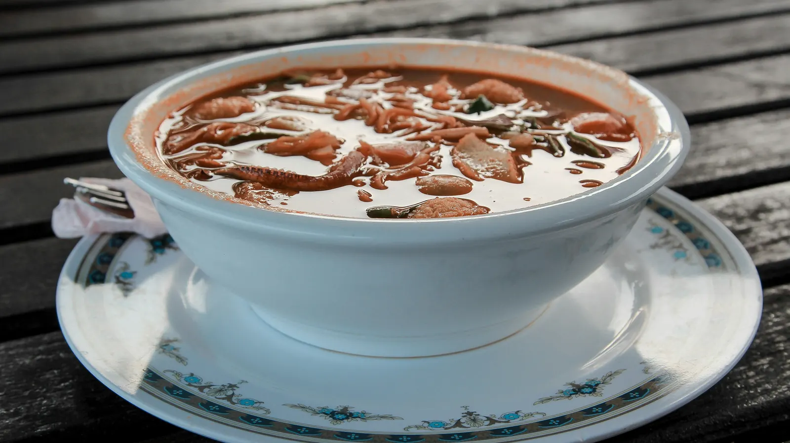 A white tureen of whole pinto beans in a thin savory broth