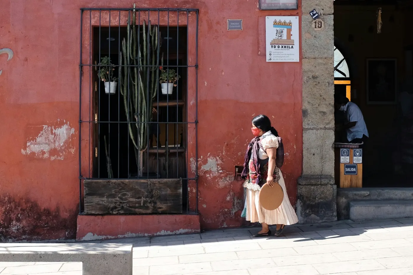 A woman in traditional dress walking past a weathered painted wall