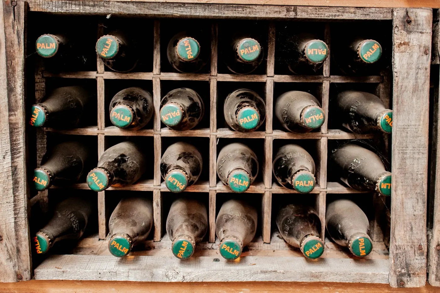 A wooden divided crate holding capped glass bottles