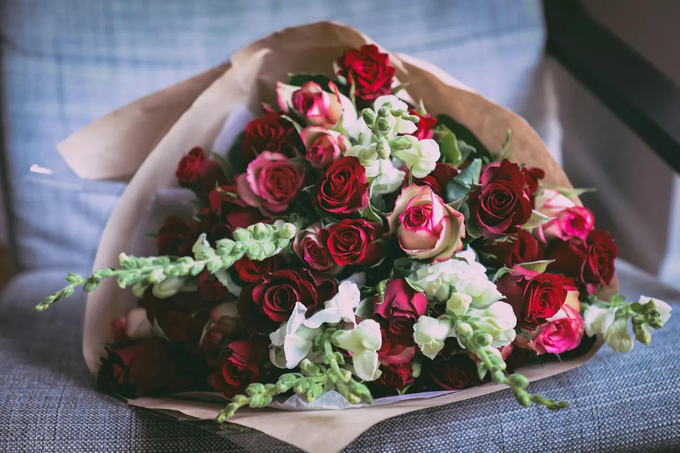 A wrapped bouquet of pink and red roses