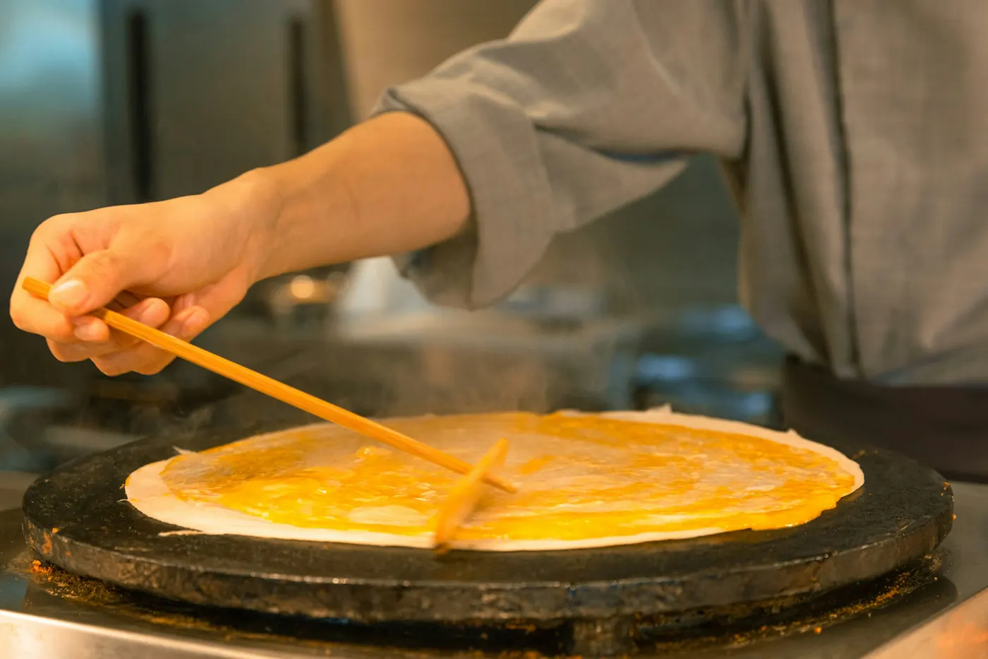 A large quesadilla filled with melted yellow cheese cooking on a flat griddle