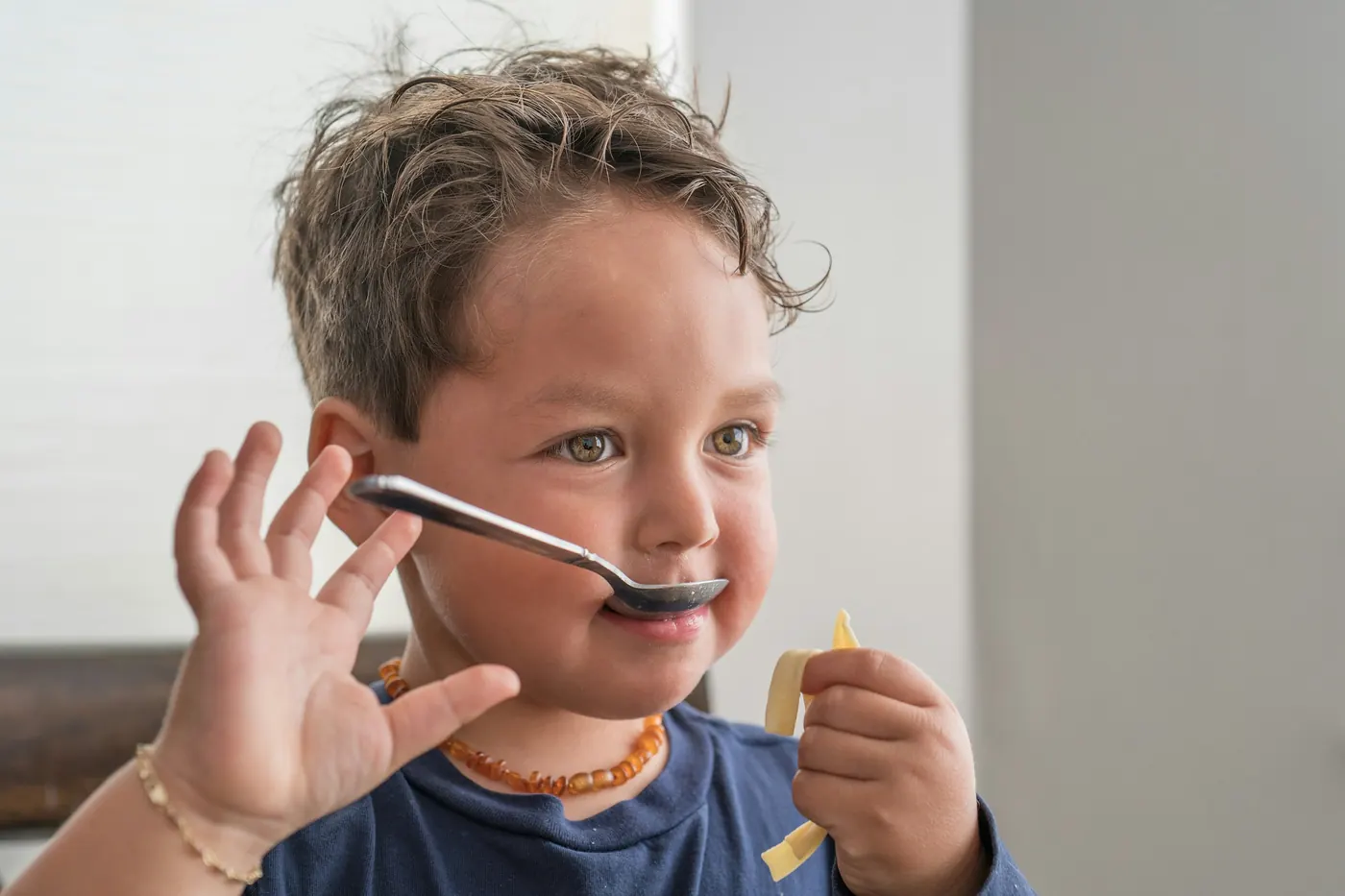 A young boy holding a spoon in his mouth at the table