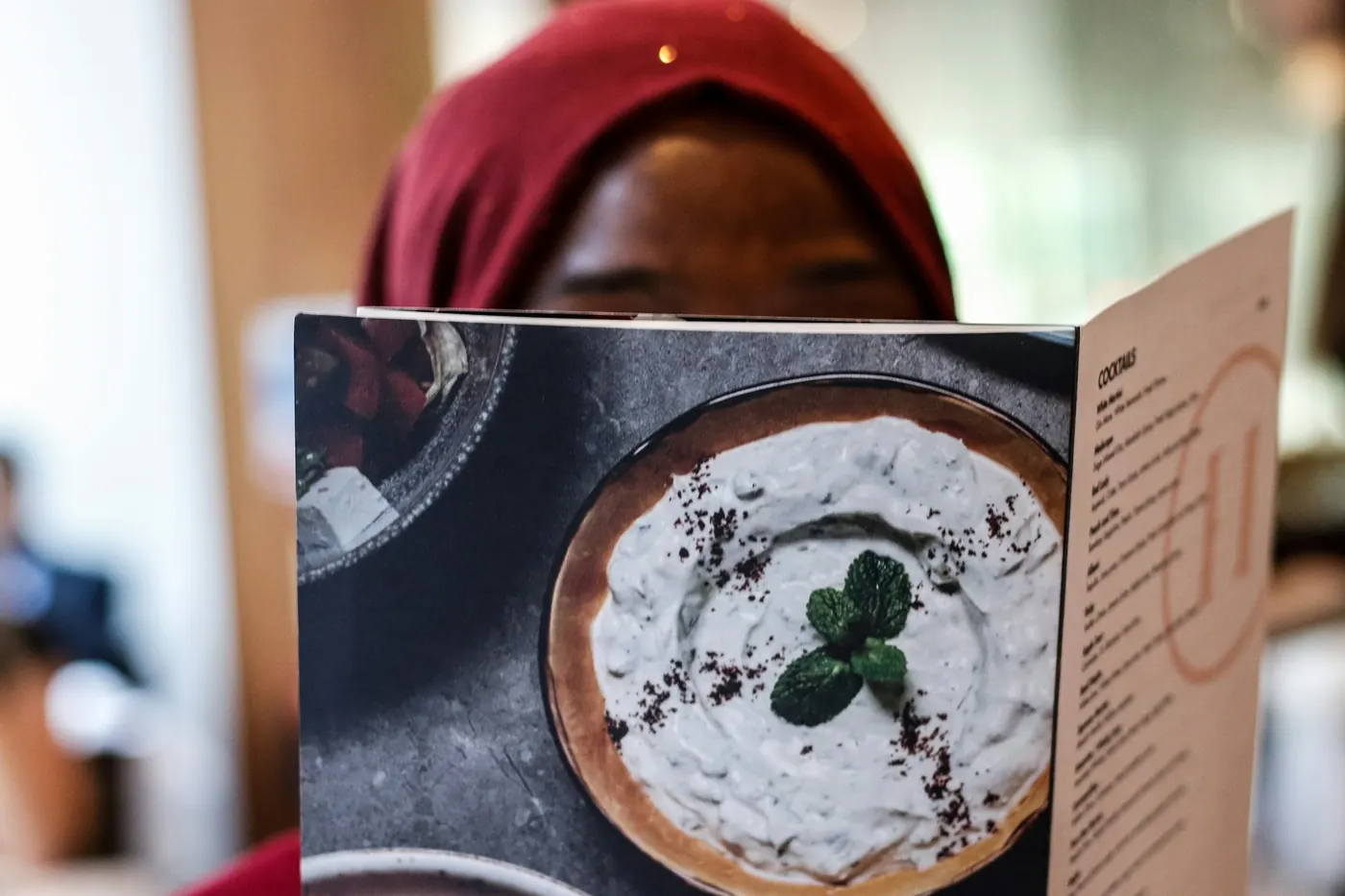 An open menu held up, showing a photograph of a dish