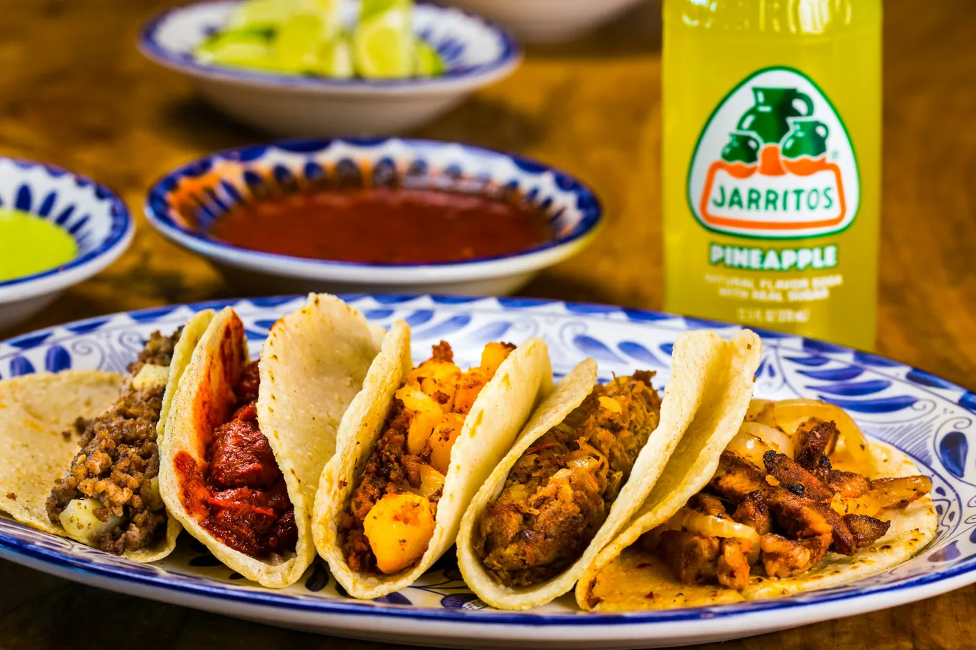 A plate of assorted tacos with several different fillings and bowls of salsa