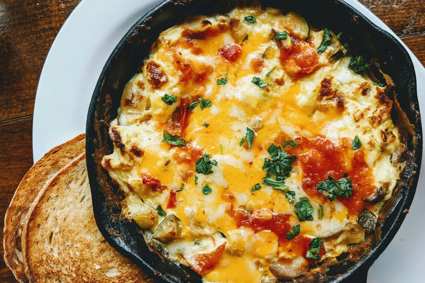 Melted cheese baked with tomato and herbs in a small cast iron skillet