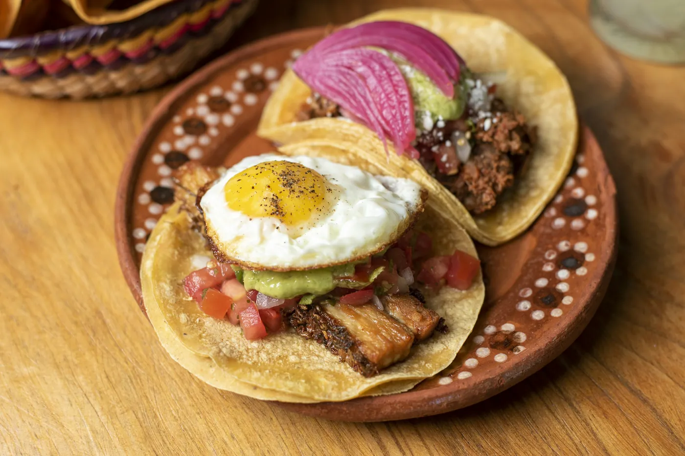 A barbacoa taco topped with a fried egg on a decorated clay plate