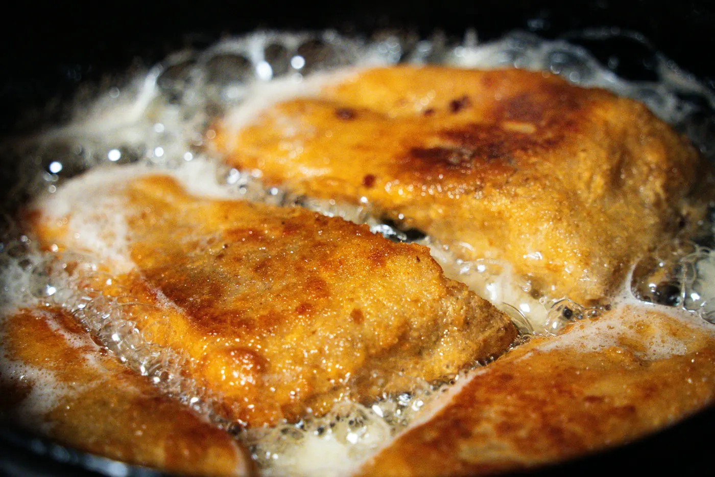 Battered food turning golden in bubbling oil