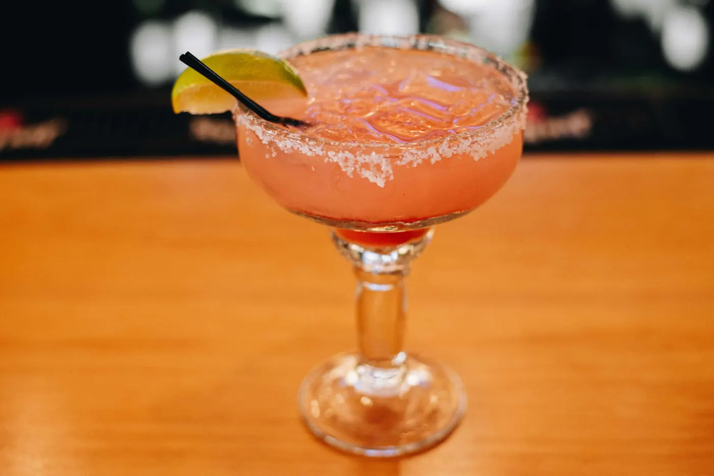 A blended pink fruit margarita in a wide coupe glass