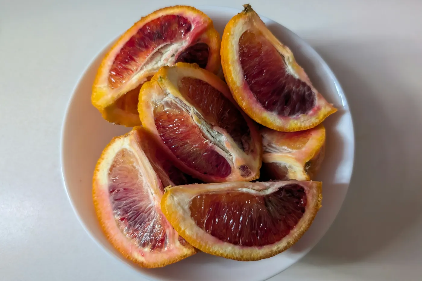 Slices of deep red blood orange arranged on a white plate
