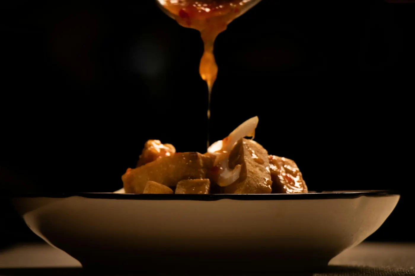Caramel sauce being drizzled from a spoon onto a dish